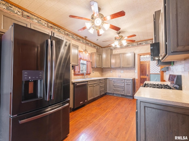 kitchen featuring appliances with stainless steel finishes, light wood-type flooring, gray cabinetry, crown molding, and sink