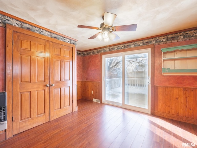 interior space with ceiling fan, light wood-type flooring, and wooden walls