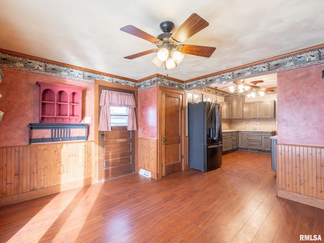 kitchen featuring ceiling fan, light hardwood / wood-style flooring, stainless steel refrigerator with ice dispenser, wood walls, and ornamental molding