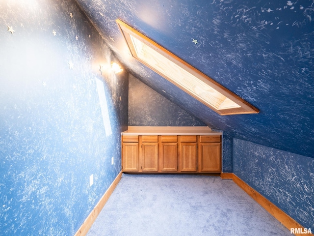 additional living space with light colored carpet and vaulted ceiling with skylight