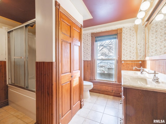 full bathroom featuring vanity, bath / shower combo with glass door, wooden walls, tile patterned flooring, and toilet