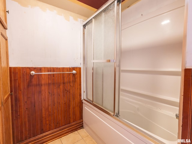 bathroom with tile patterned flooring, enclosed tub / shower combo, and wooden walls