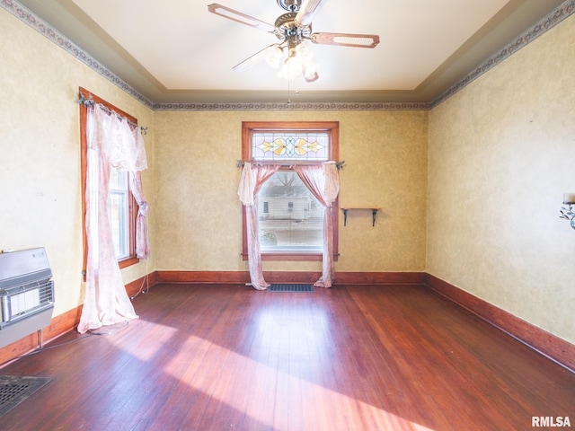 spare room with hardwood / wood-style floors, heating unit, and ceiling fan