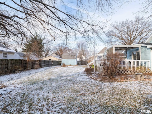 yard layered in snow with a shed and a deck