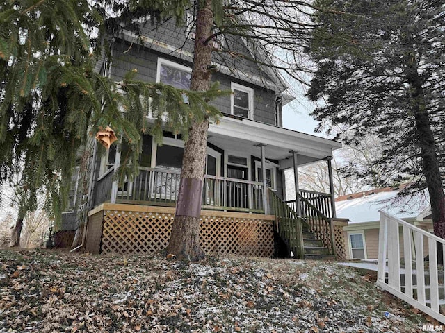 view of front of home with covered porch, ceiling fan, and stairway