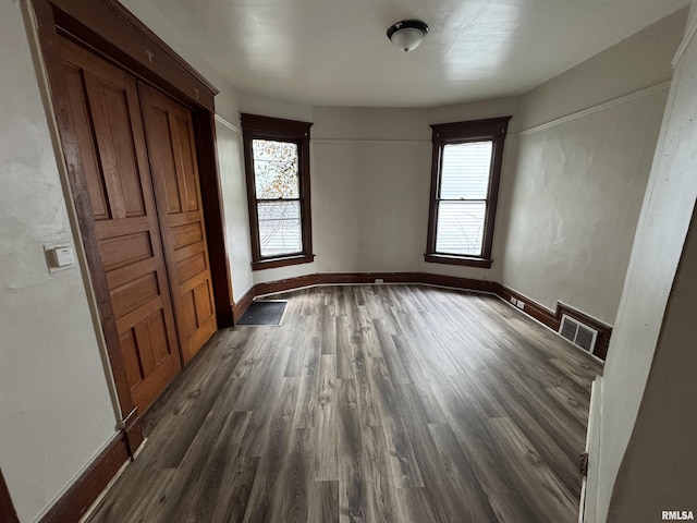 unfurnished bedroom with multiple windows and dark wood-type flooring