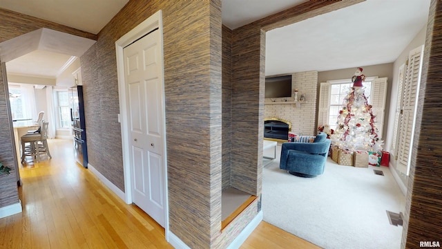 hallway with ornamental molding, light hardwood / wood-style floors, and a wealth of natural light