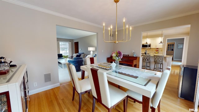 dining area with crown molding, a chandelier, and light hardwood / wood-style flooring