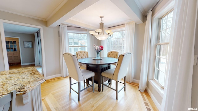 dining room with ornamental molding, an inviting chandelier, and light hardwood / wood-style flooring