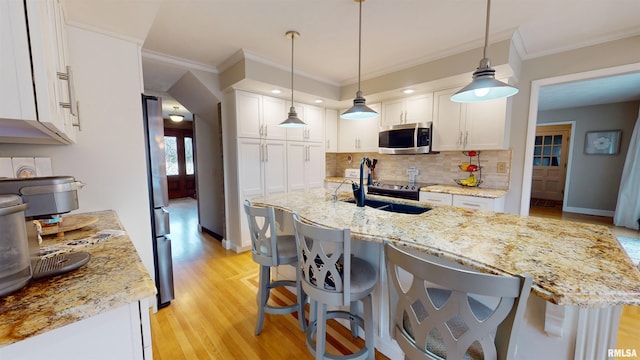 kitchen with white cabinetry, appliances with stainless steel finishes, pendant lighting, and light stone counters