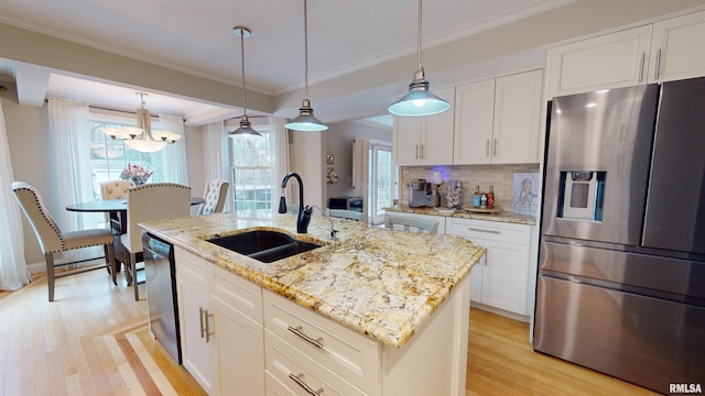 kitchen with pendant lighting, white cabinetry, sink, stainless steel appliances, and a center island with sink