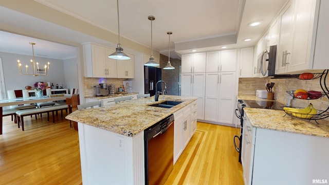 kitchen featuring pendant lighting, sink, appliances with stainless steel finishes, white cabinetry, and a center island with sink