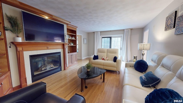 living room with a fireplace, light hardwood / wood-style floors, and a textured ceiling