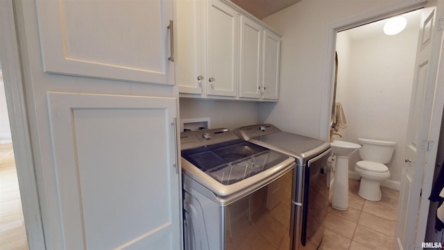 laundry area featuring cabinets, light tile patterned floors, and independent washer and dryer