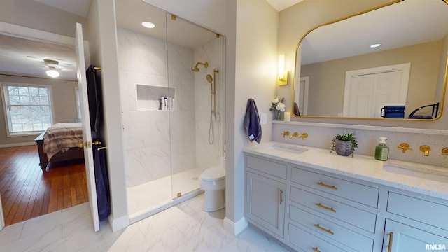 bathroom featuring vanity, a tile shower, backsplash, and toilet