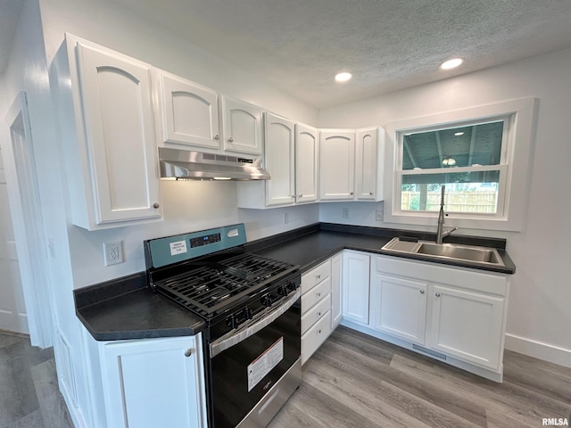 kitchen featuring gas stove, white cabinetry, and sink