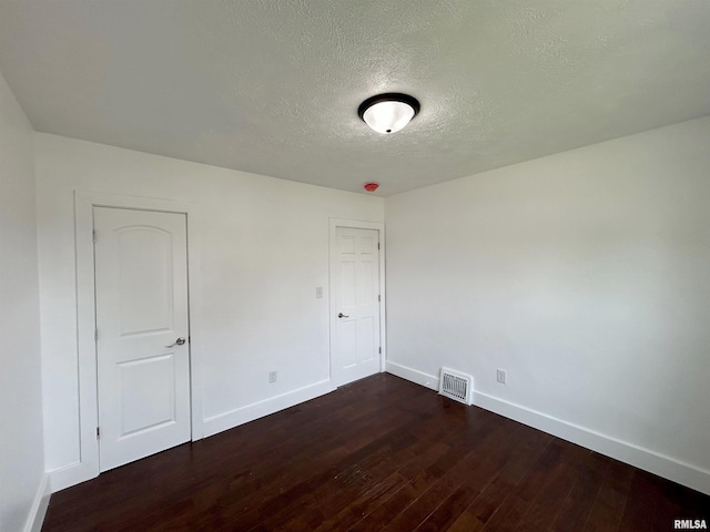 spare room with dark hardwood / wood-style flooring and a textured ceiling