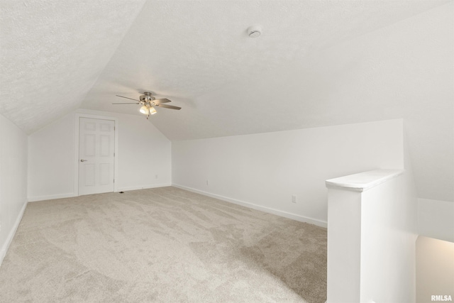 additional living space featuring a textured ceiling, ceiling fan, light carpet, and lofted ceiling