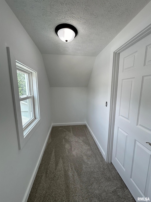 bonus room with a textured ceiling, dark carpet, and lofted ceiling