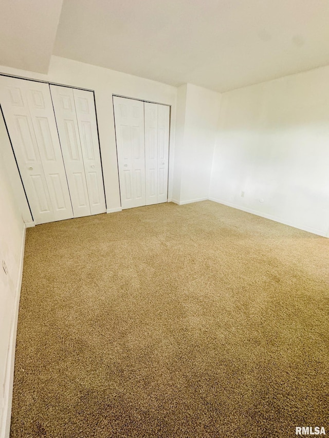 unfurnished bedroom with carpet floors and multiple closets