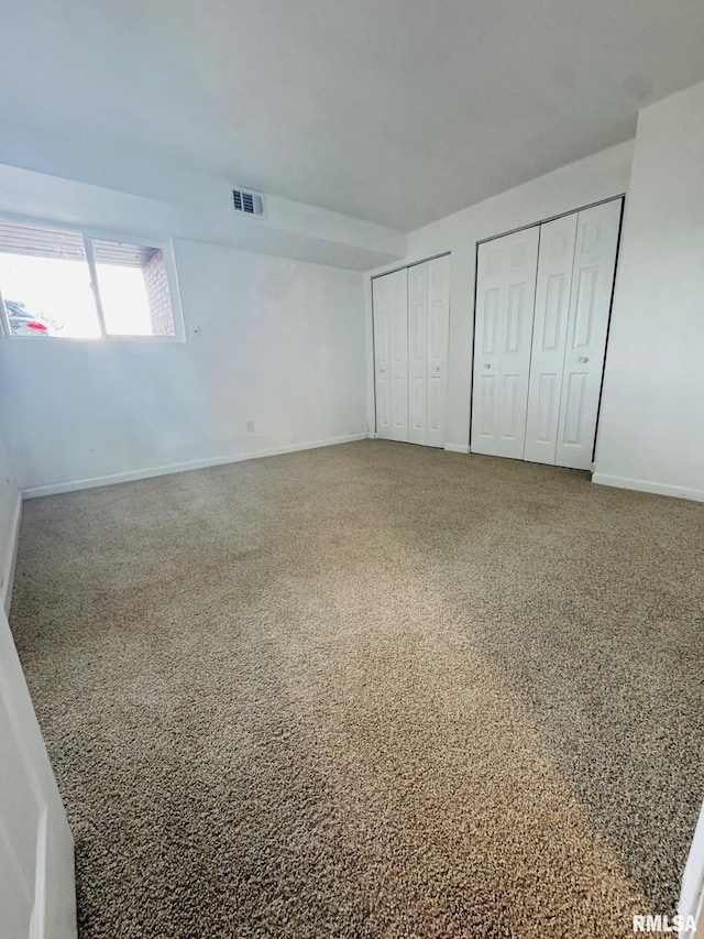 unfurnished bedroom with carpet flooring and multiple closets