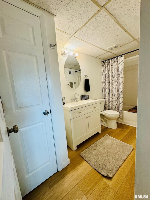 full bathroom with a paneled ceiling, shower / bath combo, hardwood / wood-style floors, vanity, and toilet