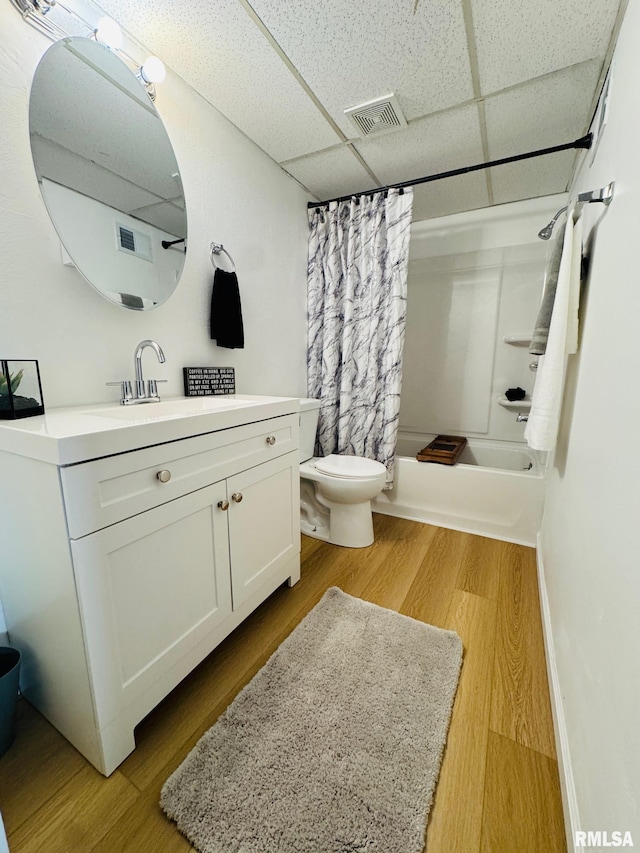 full bathroom with hardwood / wood-style floors, a paneled ceiling, shower / bathtub combination with curtain, and vanity