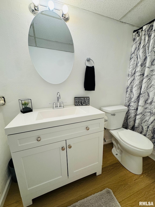 bathroom with a paneled ceiling, vanity, wood-type flooring, and toilet