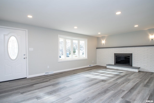 unfurnished living room featuring a brick fireplace and light hardwood / wood-style flooring