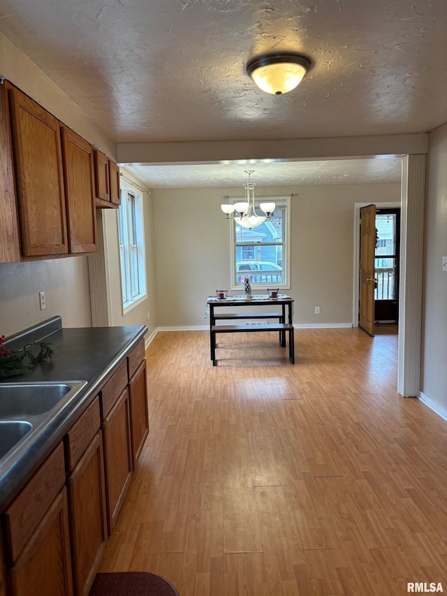 kitchen with hanging light fixtures, plenty of natural light, a chandelier, and light hardwood / wood-style flooring