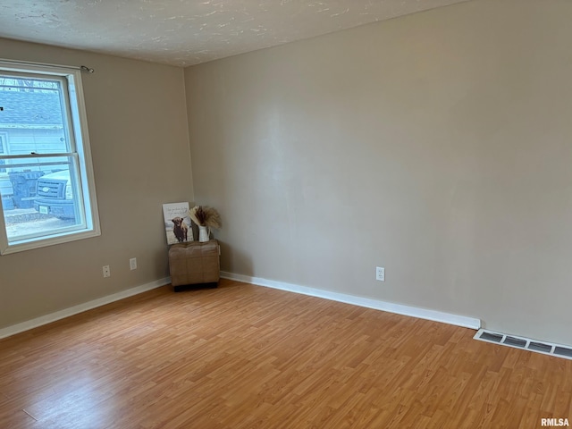 empty room with a textured ceiling and light hardwood / wood-style floors