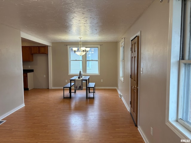 dining space featuring light hardwood / wood-style floors, a textured ceiling, and a chandelier