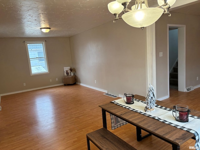 dining area featuring a chandelier, a textured ceiling, and light hardwood / wood-style flooring