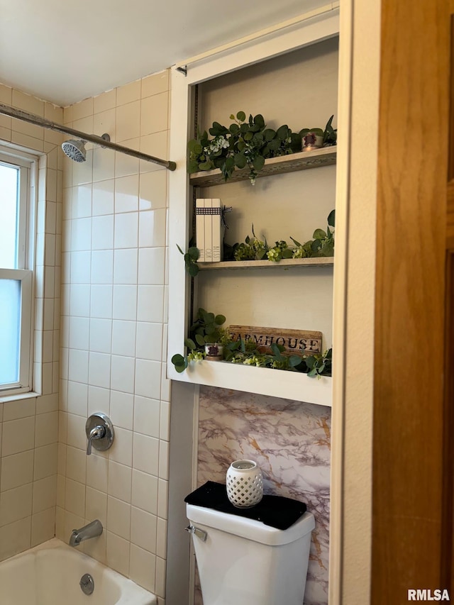 bathroom with tiled shower / bath combo and toilet