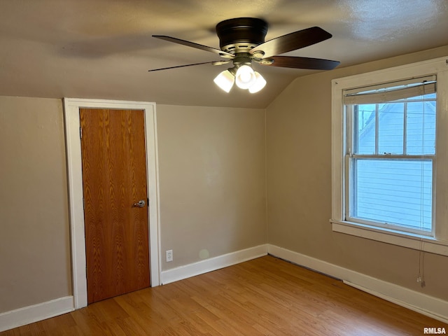 empty room featuring light wood-type flooring, vaulted ceiling, and ceiling fan