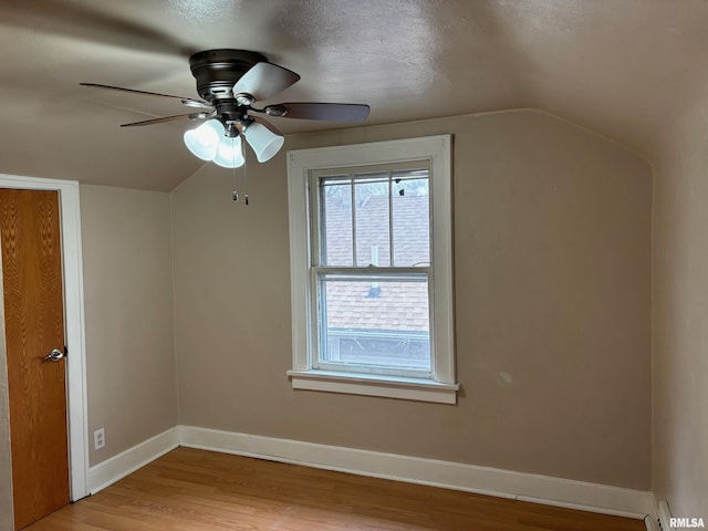 additional living space with a textured ceiling, ceiling fan, light hardwood / wood-style flooring, and lofted ceiling