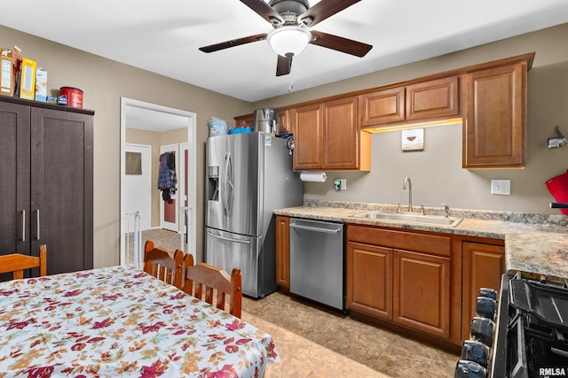 kitchen with ceiling fan, sink, stainless steel appliances, and light stone counters