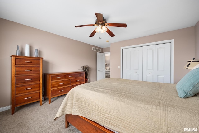 bedroom with ceiling fan, light carpet, and a closet