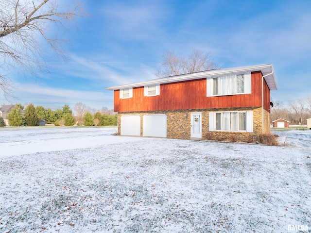 snow covered house featuring a garage