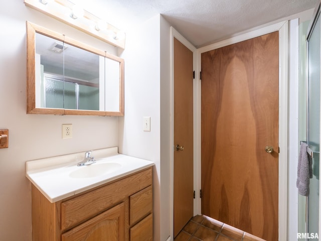 bathroom with tile patterned flooring, vanity, and a textured ceiling