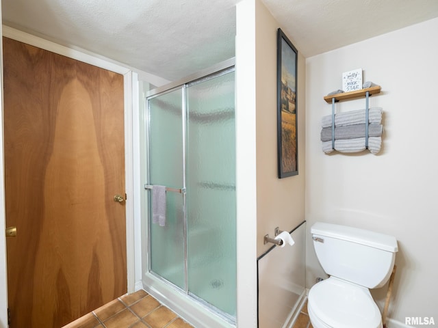 bathroom with tile patterned floors, a shower with door, and a textured ceiling