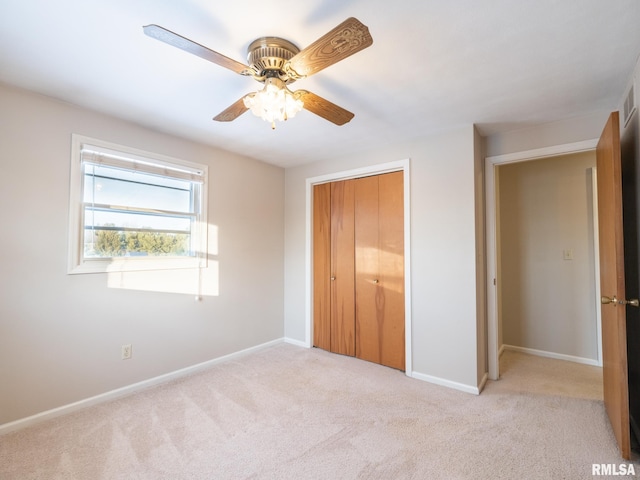 unfurnished bedroom with ceiling fan, light carpet, and a closet