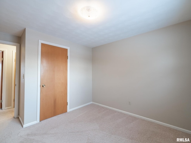 unfurnished bedroom featuring a closet and light colored carpet