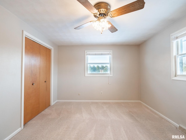 unfurnished bedroom featuring ceiling fan, a closet, and light carpet