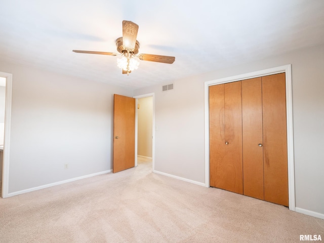 unfurnished bedroom with ceiling fan, light colored carpet, and a closet