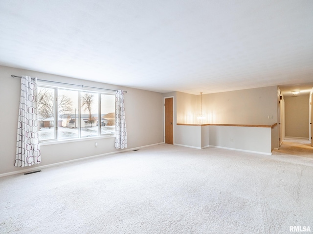 carpeted spare room featuring an inviting chandelier