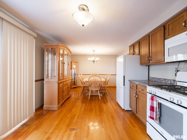 kitchen with light hardwood / wood-style flooring, pendant lighting, white appliances, and a notable chandelier