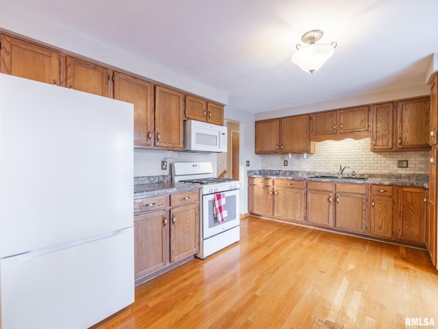 kitchen featuring backsplash, light hardwood / wood-style flooring, white appliances, and sink