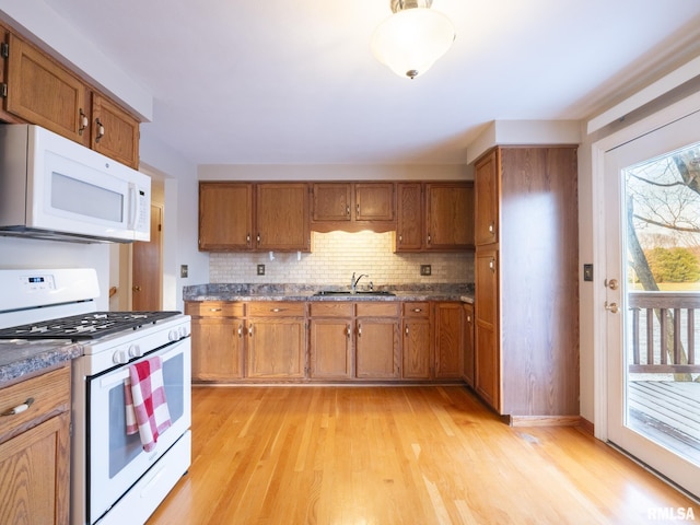 kitchen featuring white appliances, tasteful backsplash, light hardwood / wood-style flooring, and sink