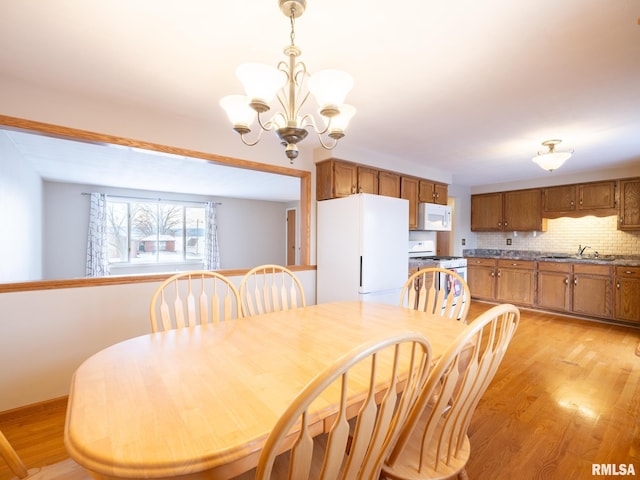 dining space featuring light hardwood / wood-style floors, an inviting chandelier, and sink